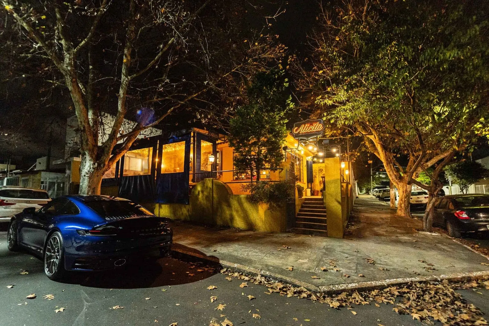 Fachada do Alicita Bistrô à noite, entre árvores e luzes, em Itapetininga