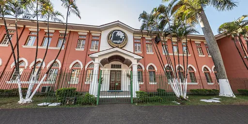 Fachada do Colégio Anglo de Itapetininga, prédio de tijolos aparentes com palmeiras na frente