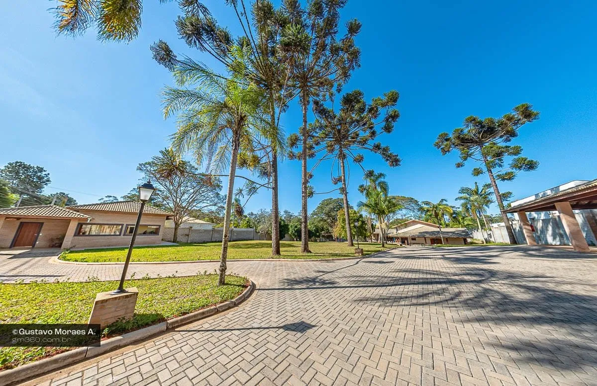 Jardim do Araucárias Residencial Sênior com palmeiras, araucárias e caminho de piso intertravado até as casas térreas