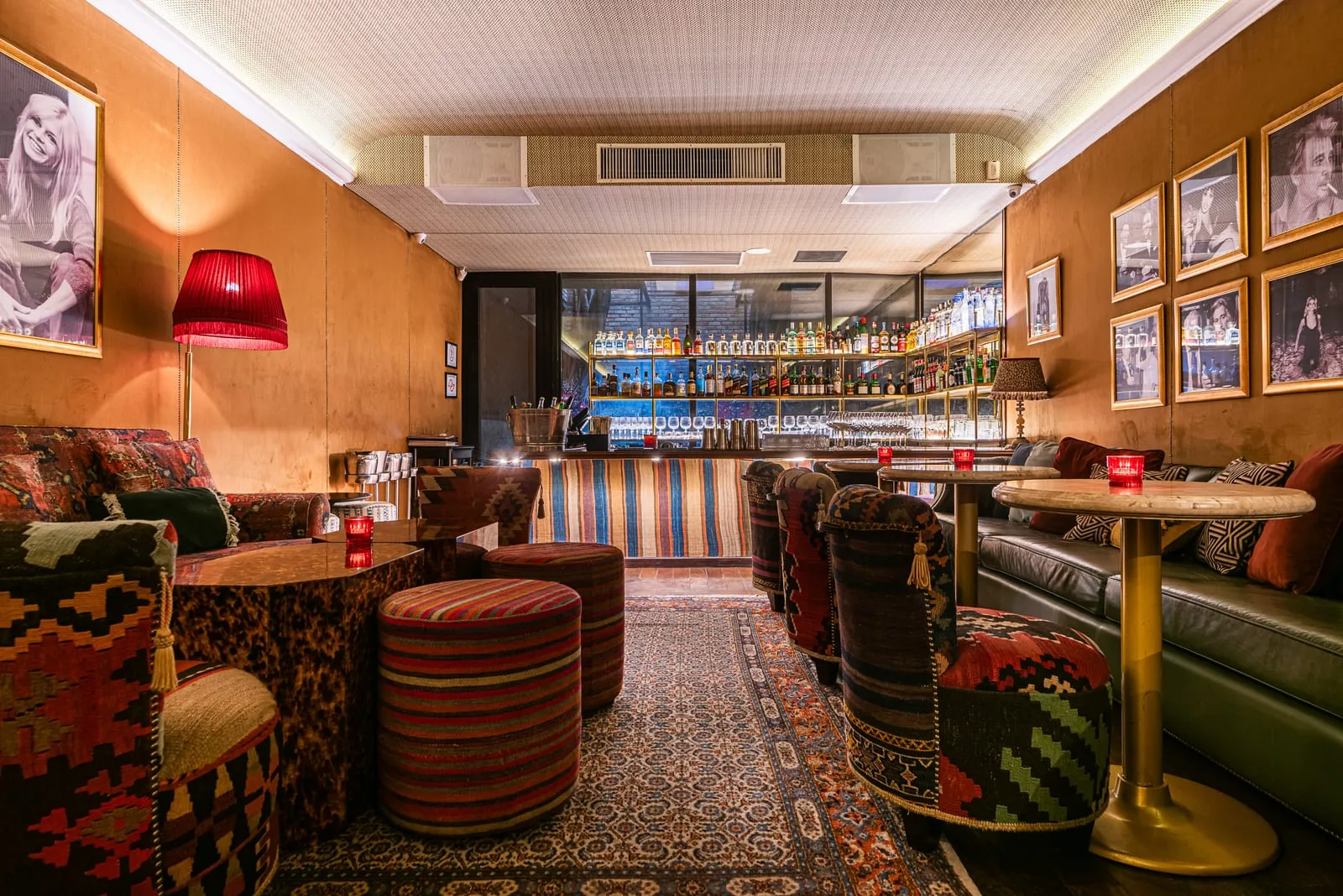 Salão do Bar do Vaticano com paredes revestidas de madeira, fotos em preto e branco de moldura dourada, poltronas forradas de kilim e, ao fundo, o balcão com prateleiras de garrafas iluminadas