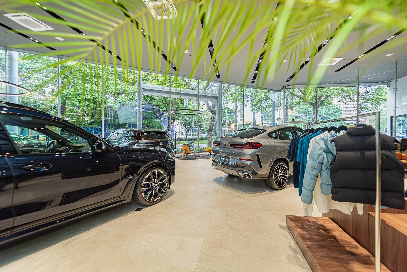 BMW preto sob o forro de plantas pendentes, com arara de jaquetas e outros modelos ao fundo