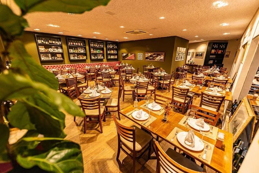 Salão da Cantina Castellammare, em Itapetininga, com mesas postas e adega ao fundo