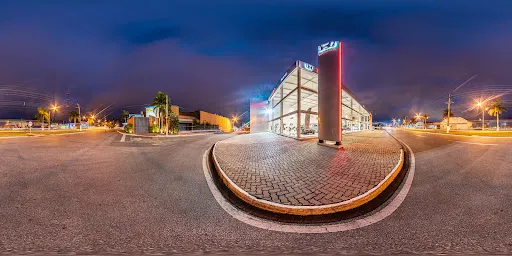 Panorama noturno da fachada envidraçada da Honda Hipervel, em Itapetininga, com o totem iluminado