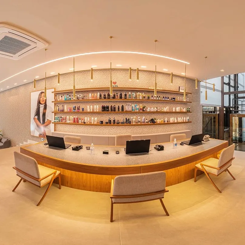 Recepção do salão C.Kamura, em São Paulo, em panorâmica 360°, com balcão curvo de madeira e prateleiras de produtos