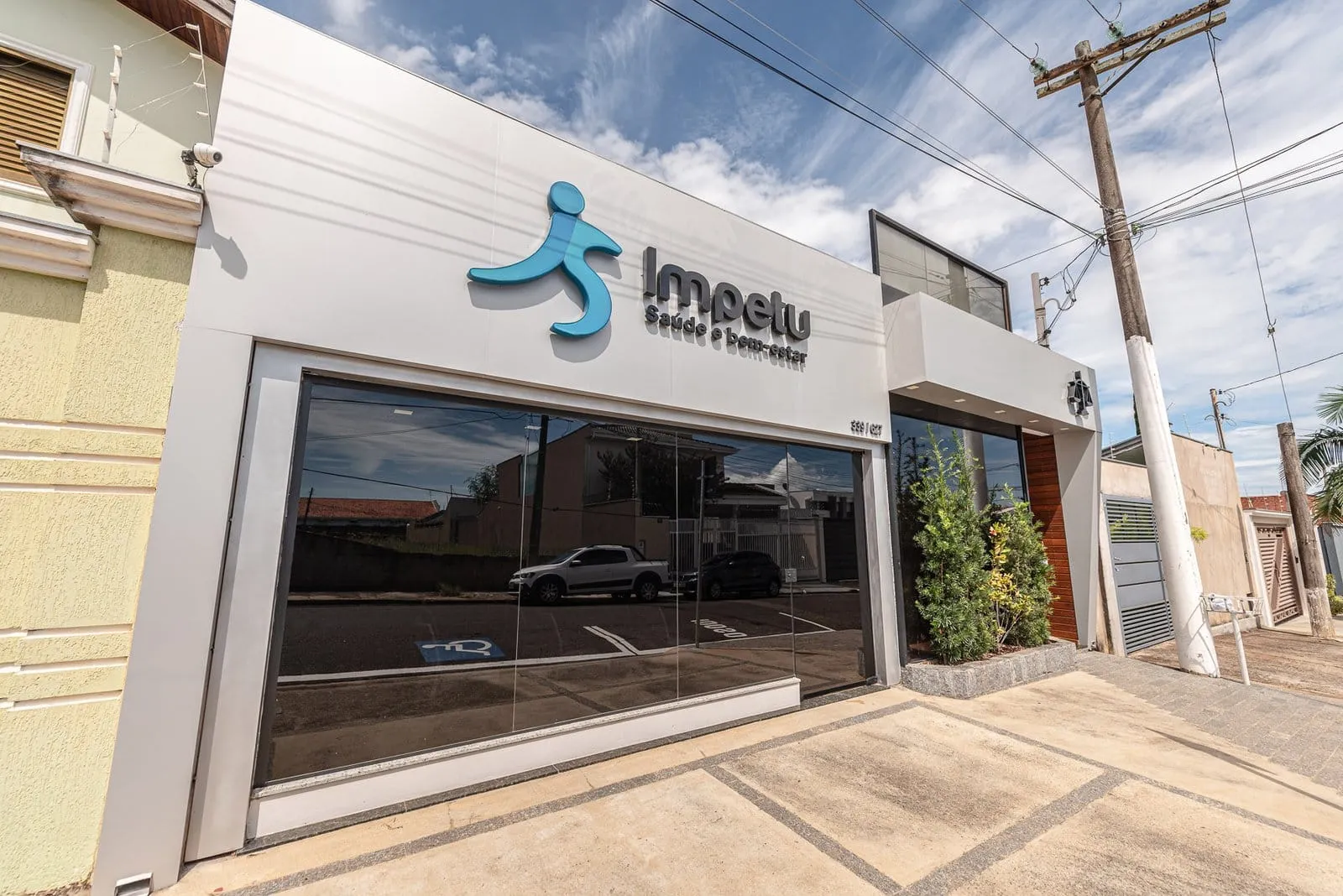Fachada da Clínica Impetu em Itapetininga, com vitrine de vidro escuro e o logotipo azul acima da porta