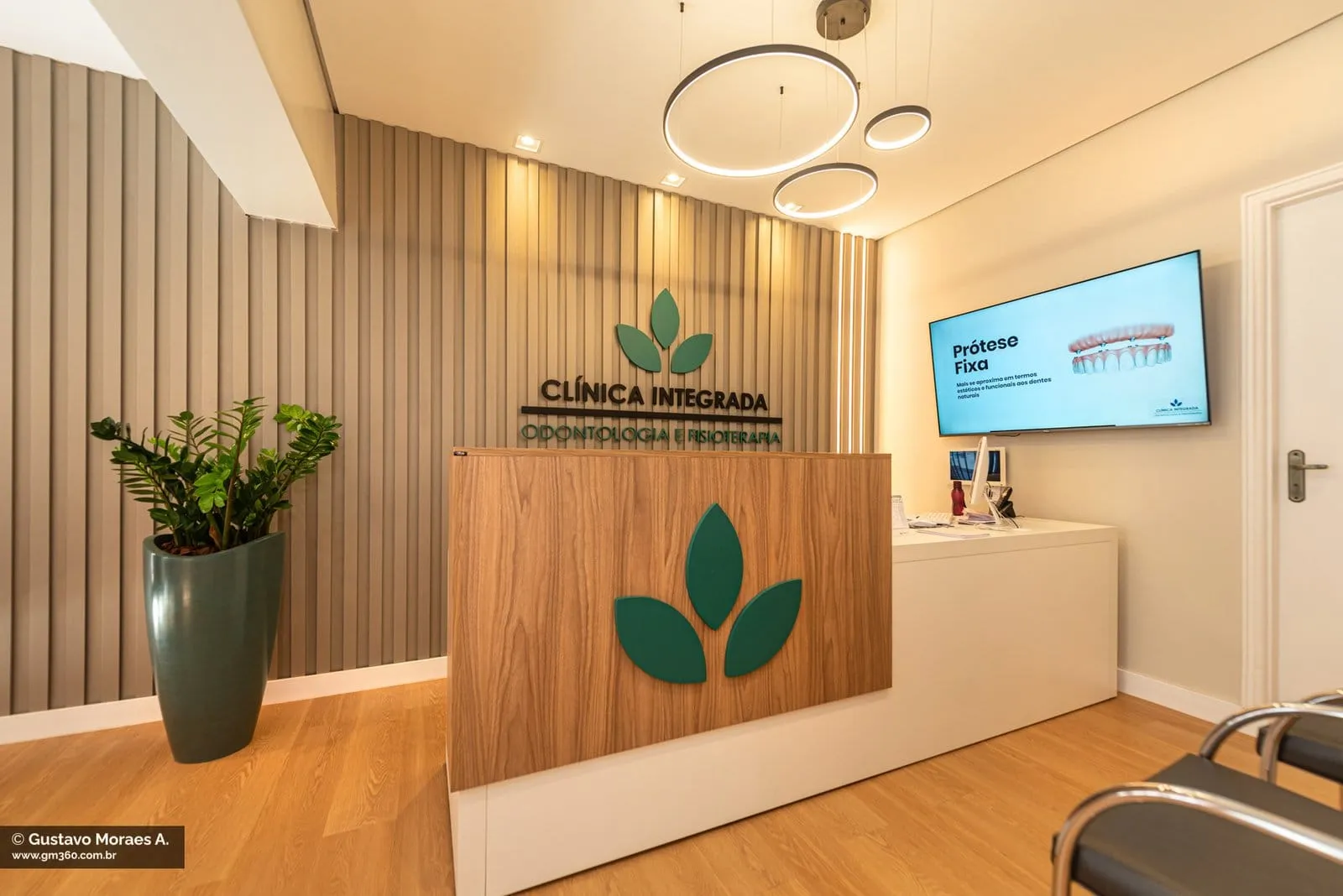 Recepção da Clínica Integrada com painel ripado e logotipo de folhas verdes