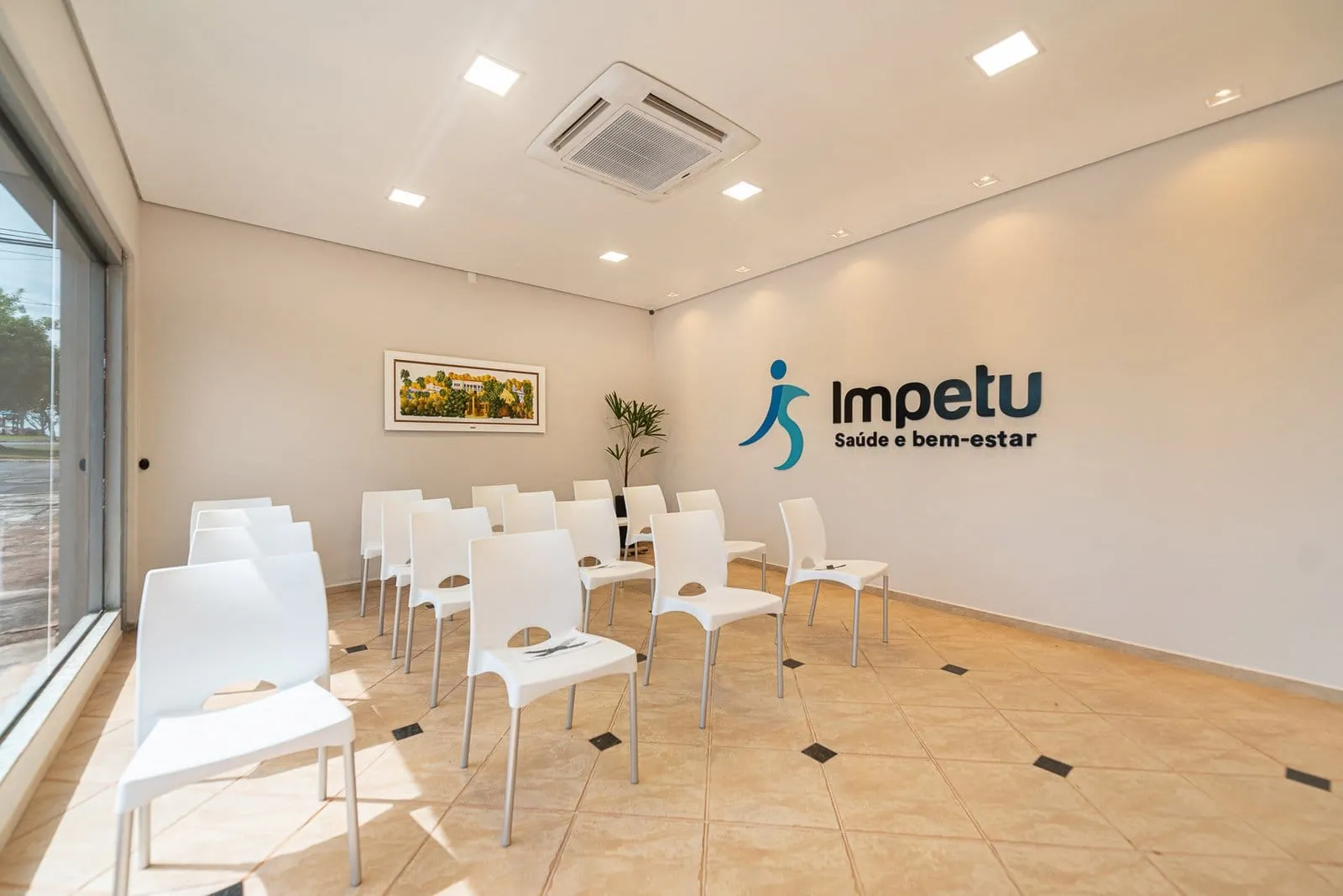 Sala com cadeiras brancas e o logotipo da Impetu Saúde e Bem-estar