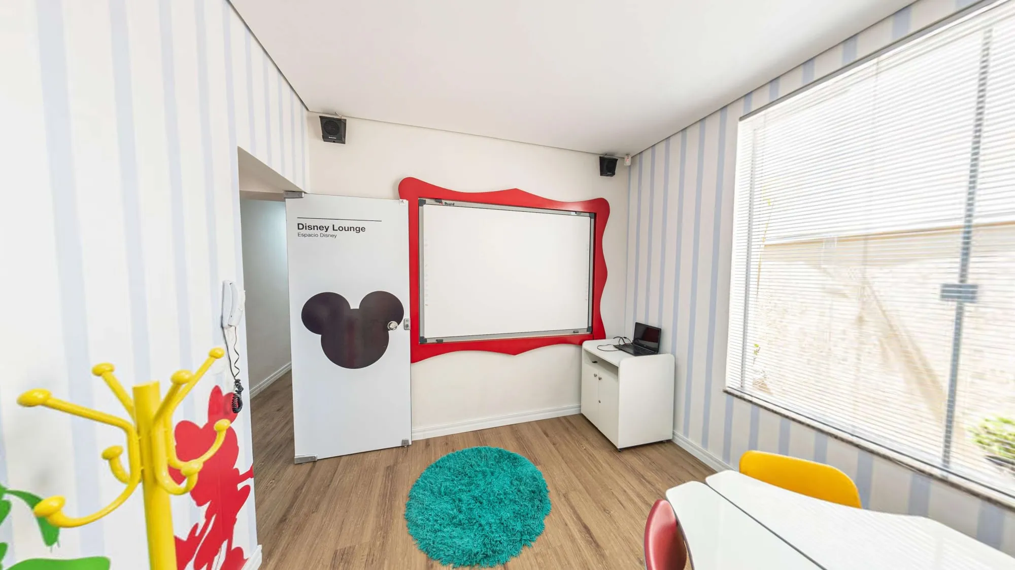 Disney Lounge do CNA Itapetininga, com lousa de moldura vermelha, porta com a silhueta do Mickey e cabideiro amarelo