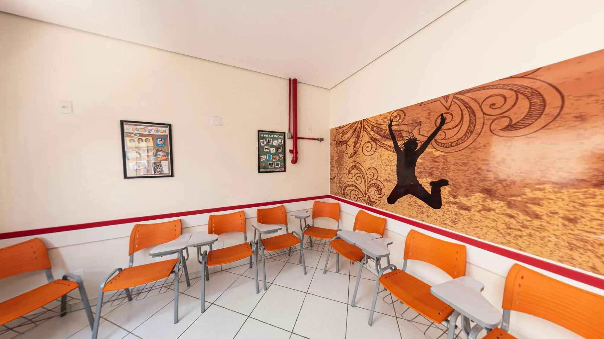 Sala Teens do CNA Itapetininga, com cadeiras universitárias laranja e painel de um jovem saltando no deserto