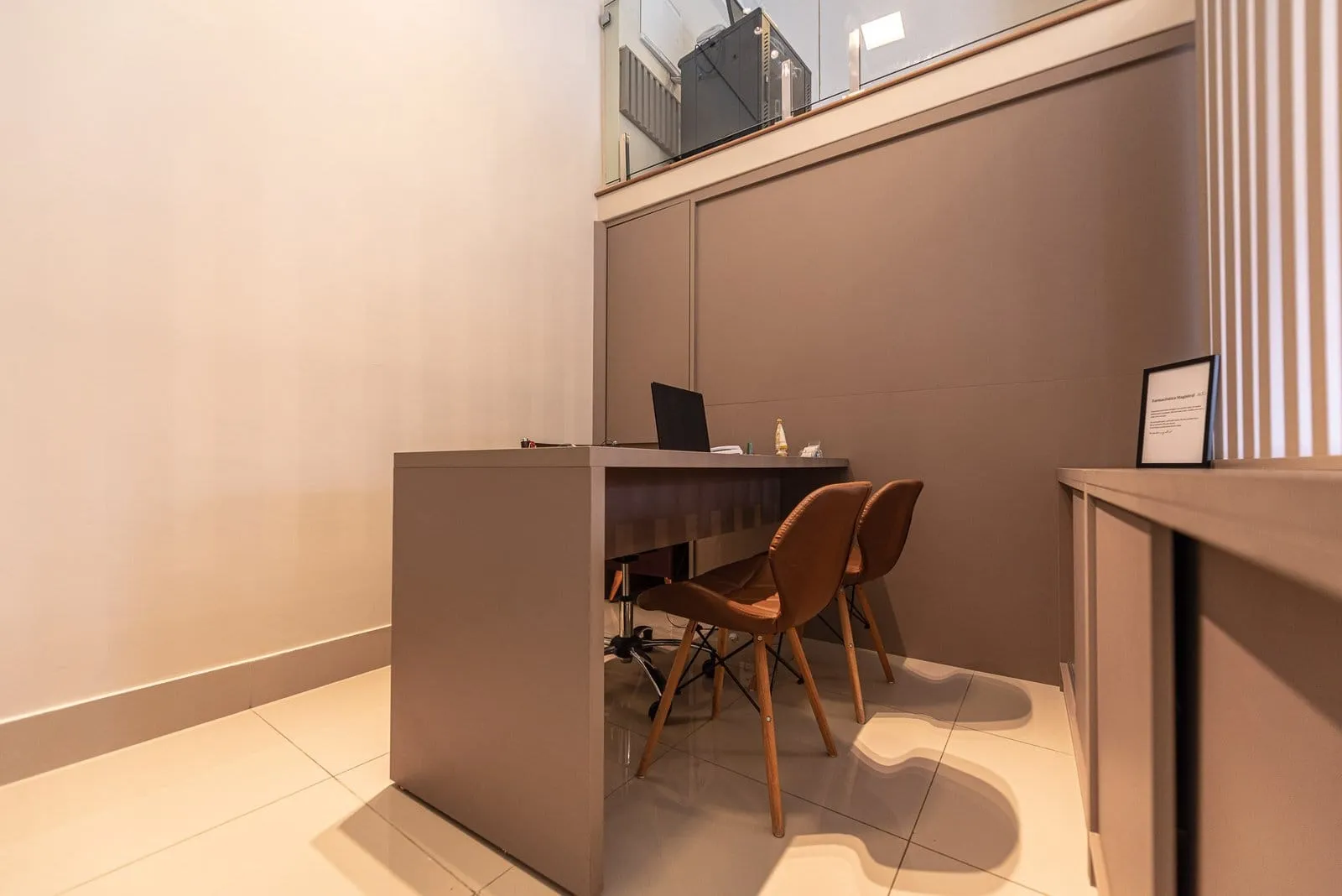Sala de atendimento com mesa, notebook e duas cadeiras de madeira
