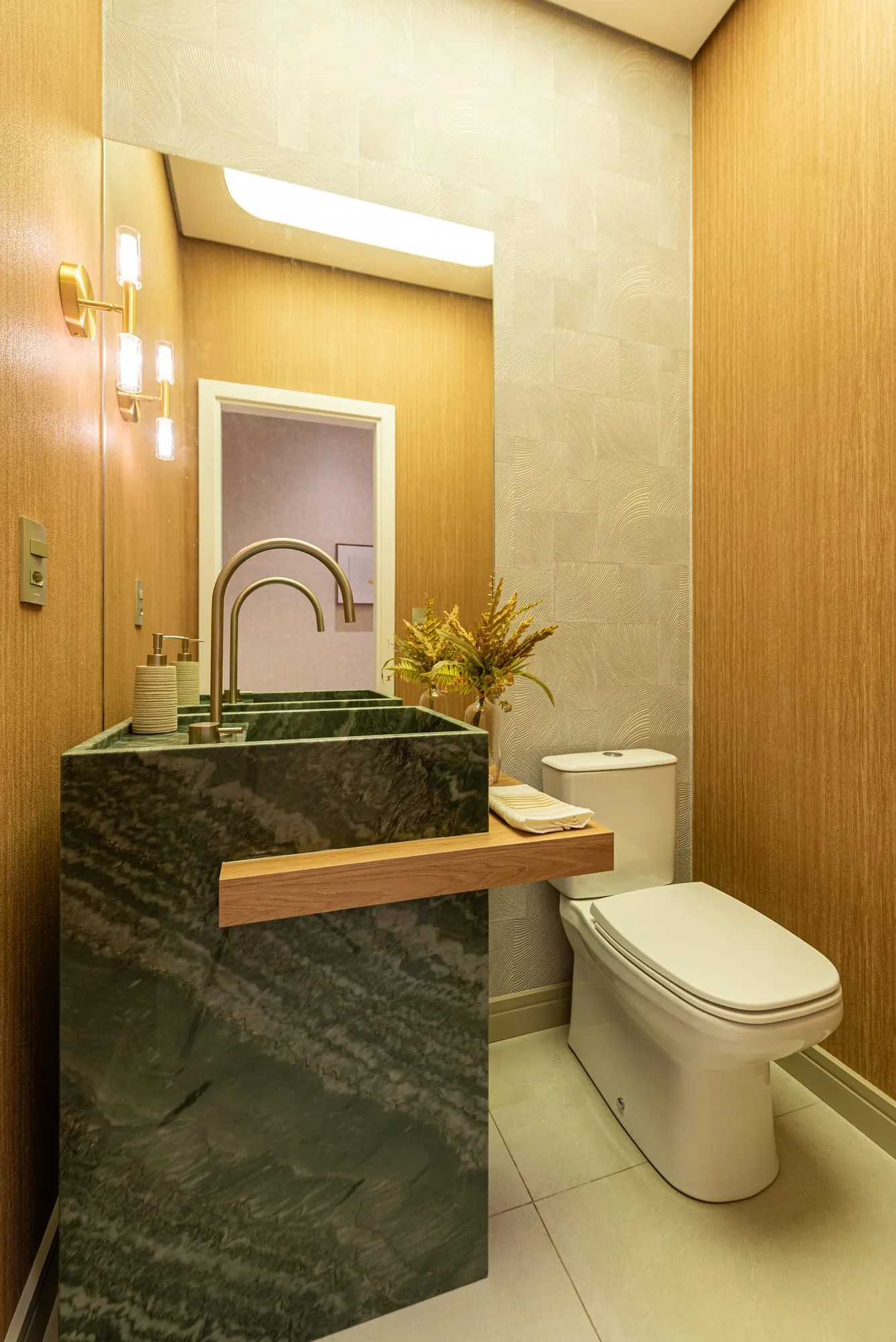 Lavabo do decorado Grand'Oro Vila Barth com bancada esculpida em mármore verde e metais dourados