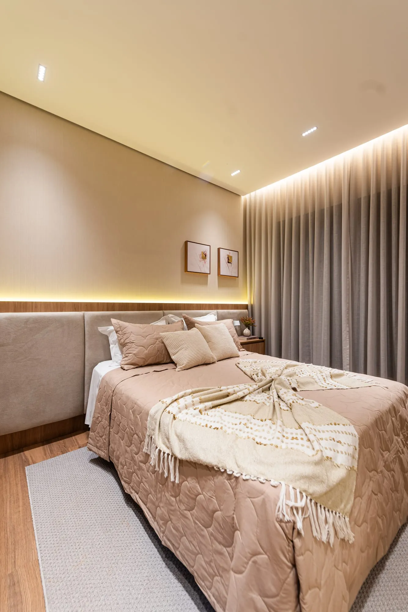 Suíte 3 com cabeceira estofada, iluminação indireta, roupa de cama rosé e cortinas do piso ao teto