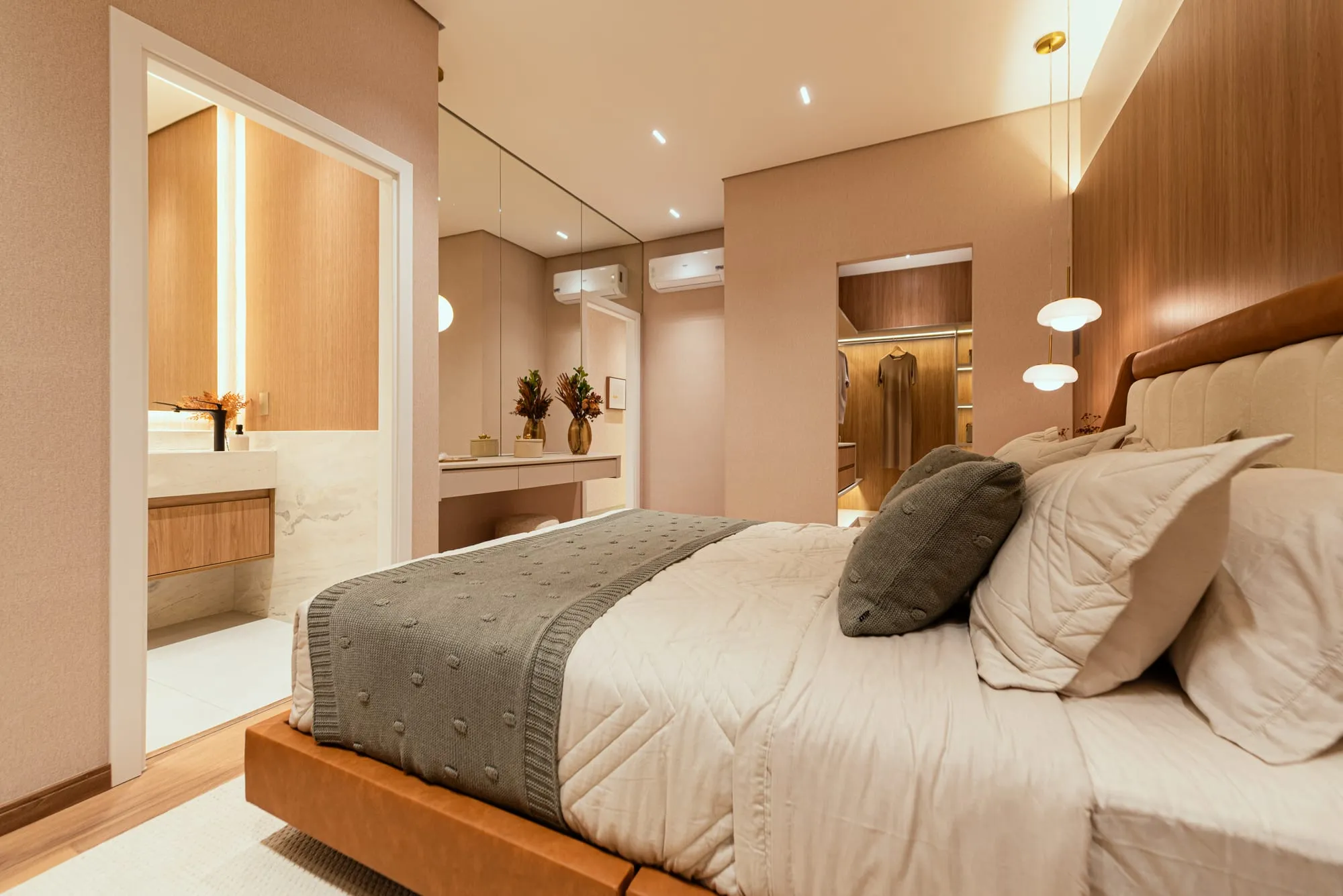 Suíte master vista da cama, com acesso ao banho em mármore, penteadeira e closet ao fundo