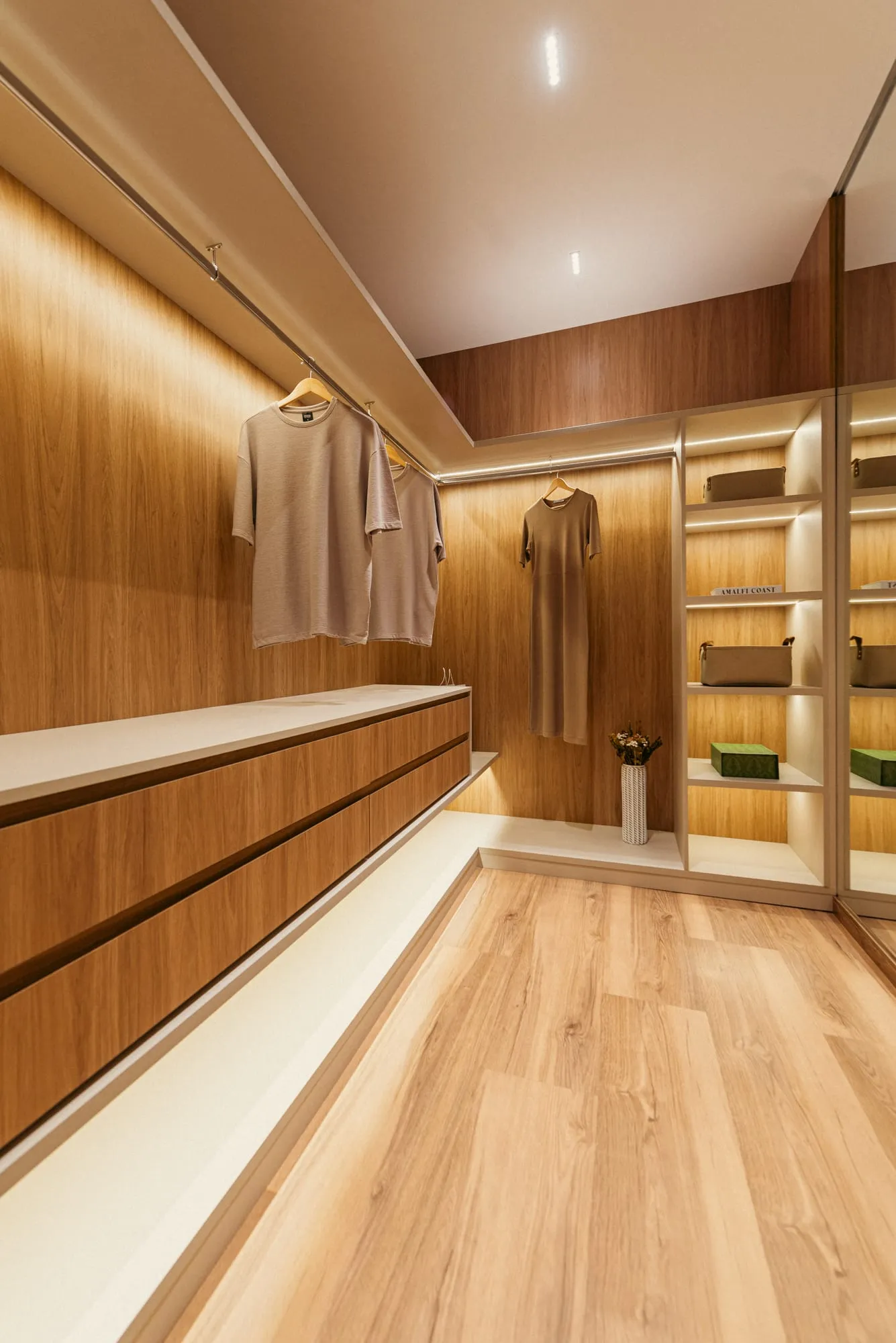 Closet da suíte master com marcenaria em madeira, gaveteiro, cabideiro e nichos iluminados