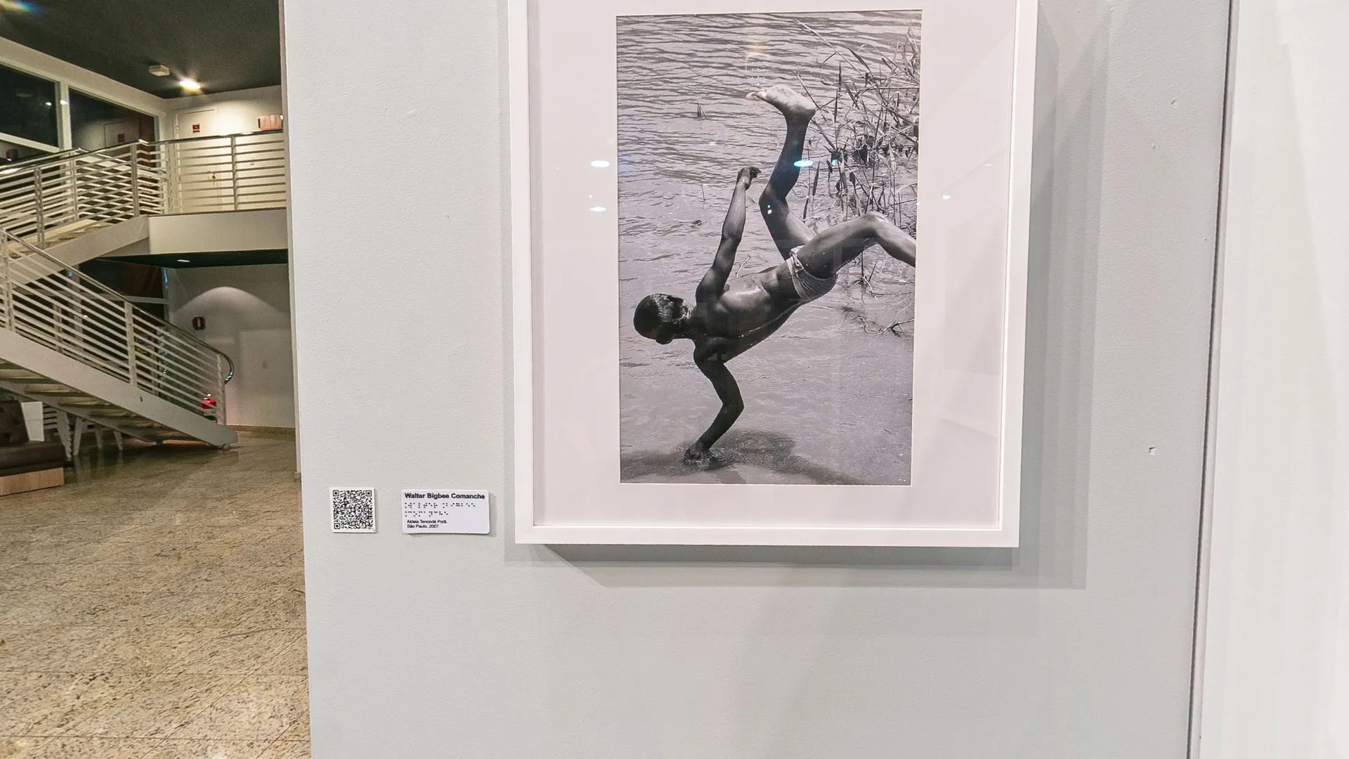 Fotografia de Walter Bigbee (Comanche) de um jovem saltando no rio, emoldurada no biombo da exposição Herança Compartilhada