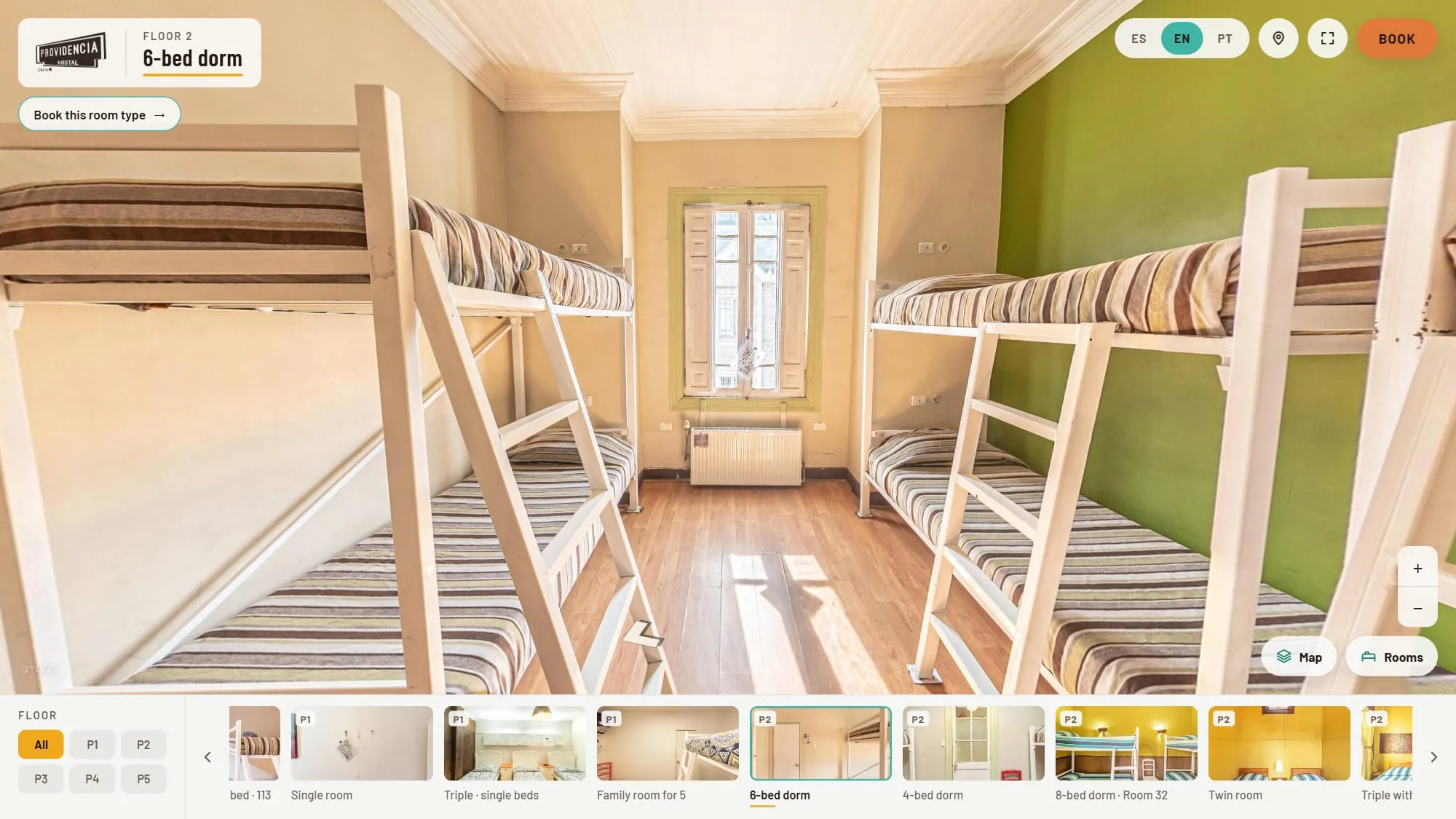 Six-bed dorm on floor 2 of Hostal Providencia shown in 360°, with white bunk beds on both sides, a green accent wall, a tall window at the end and the Book this room type button under the title