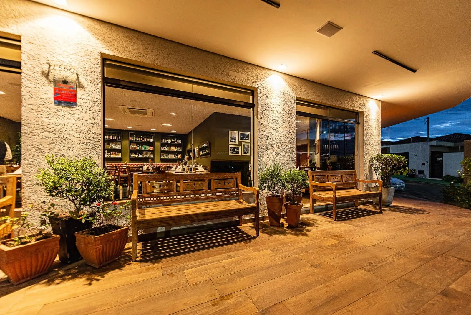 Varanda coberta da Cantina Castellammare com bancos de madeira e vasos de plantas