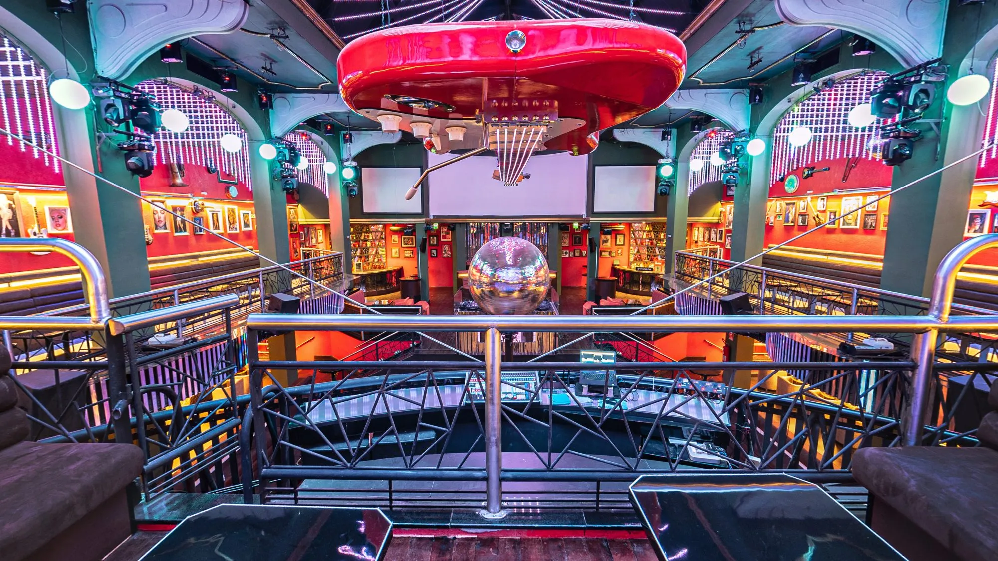 Vista dos camarotes da Limelight, no alto, com mesas escuras junto à grade de metal sobre a pista, o globo espelhado, a guitarra vermelha gigante no teto e, do outro lado, a cabine do DJ e as galerias com retratos