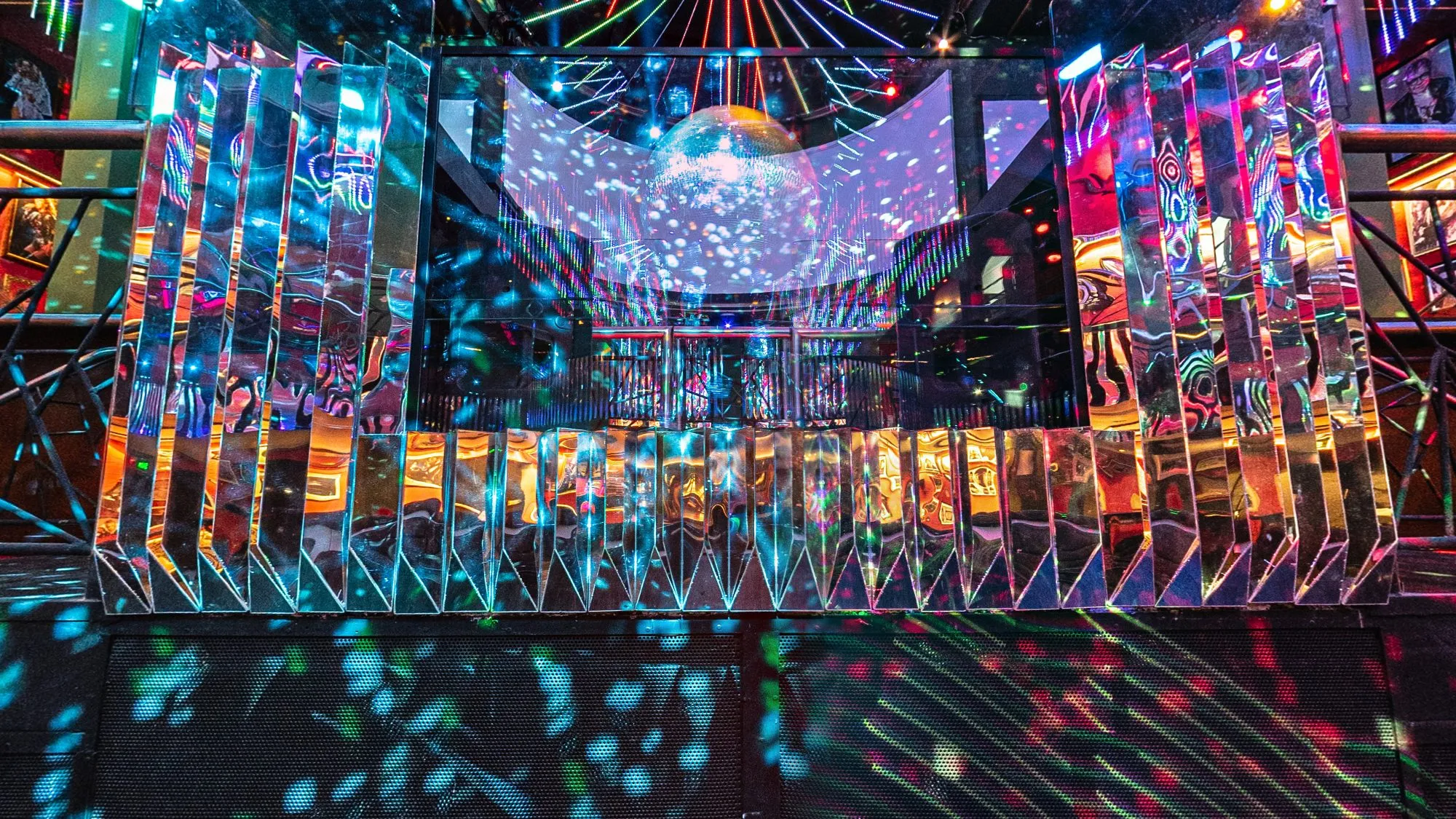 Palco da cabine do DJ da Limelight, casa noturna na Vila Olímpia, em São Paulo, revestido de lâminas espelhadas que refletem pontos de luz colorida, com o globo espelhado acima e a casa vazia