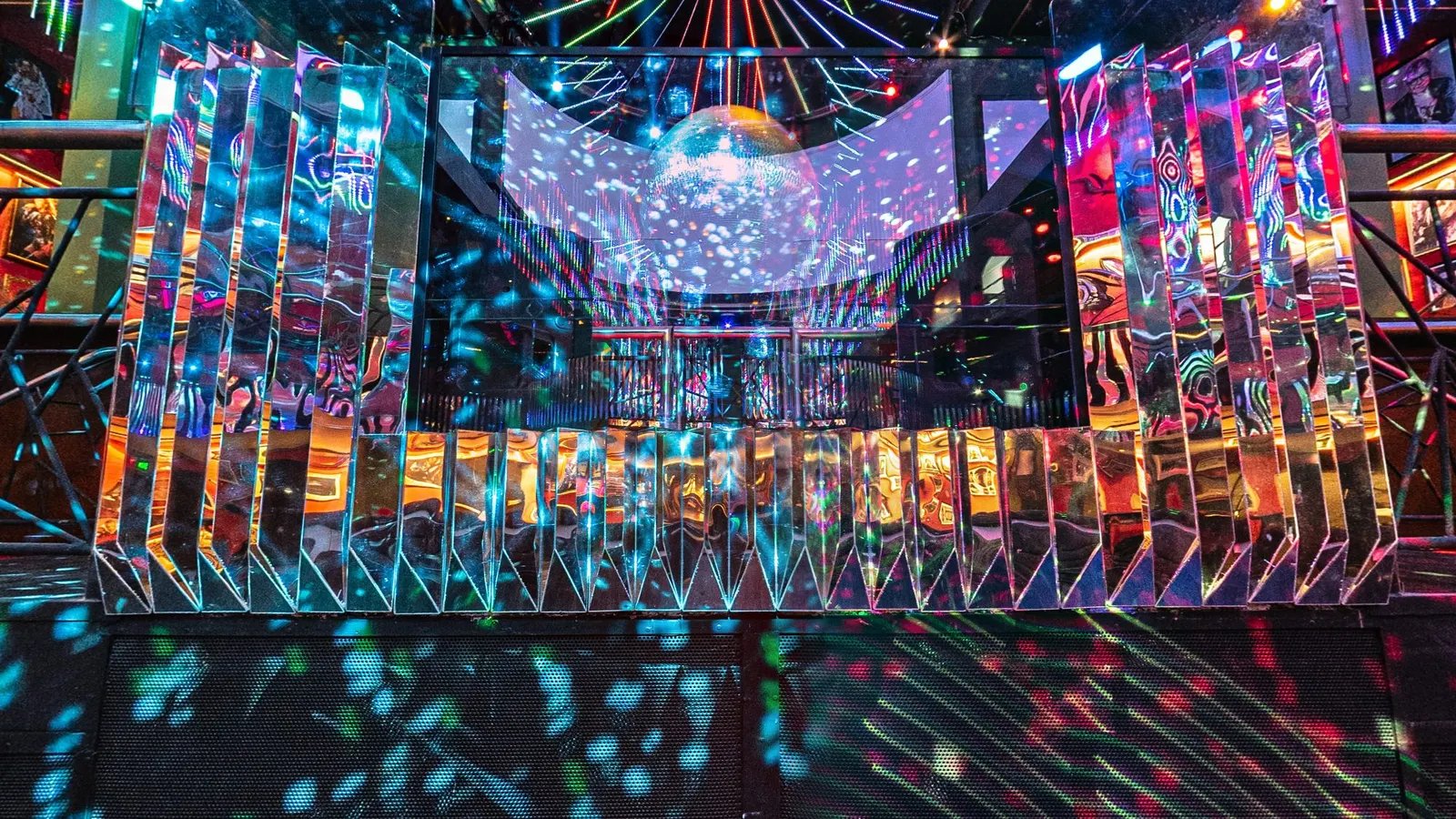Palco da cabine do DJ da Limelight, casa noturna na Vila Olímpia, em São Paulo, revestido de lâminas espelhadas que refletem pontos de luz colorida, com o globo espelhado acima e a casa vazia