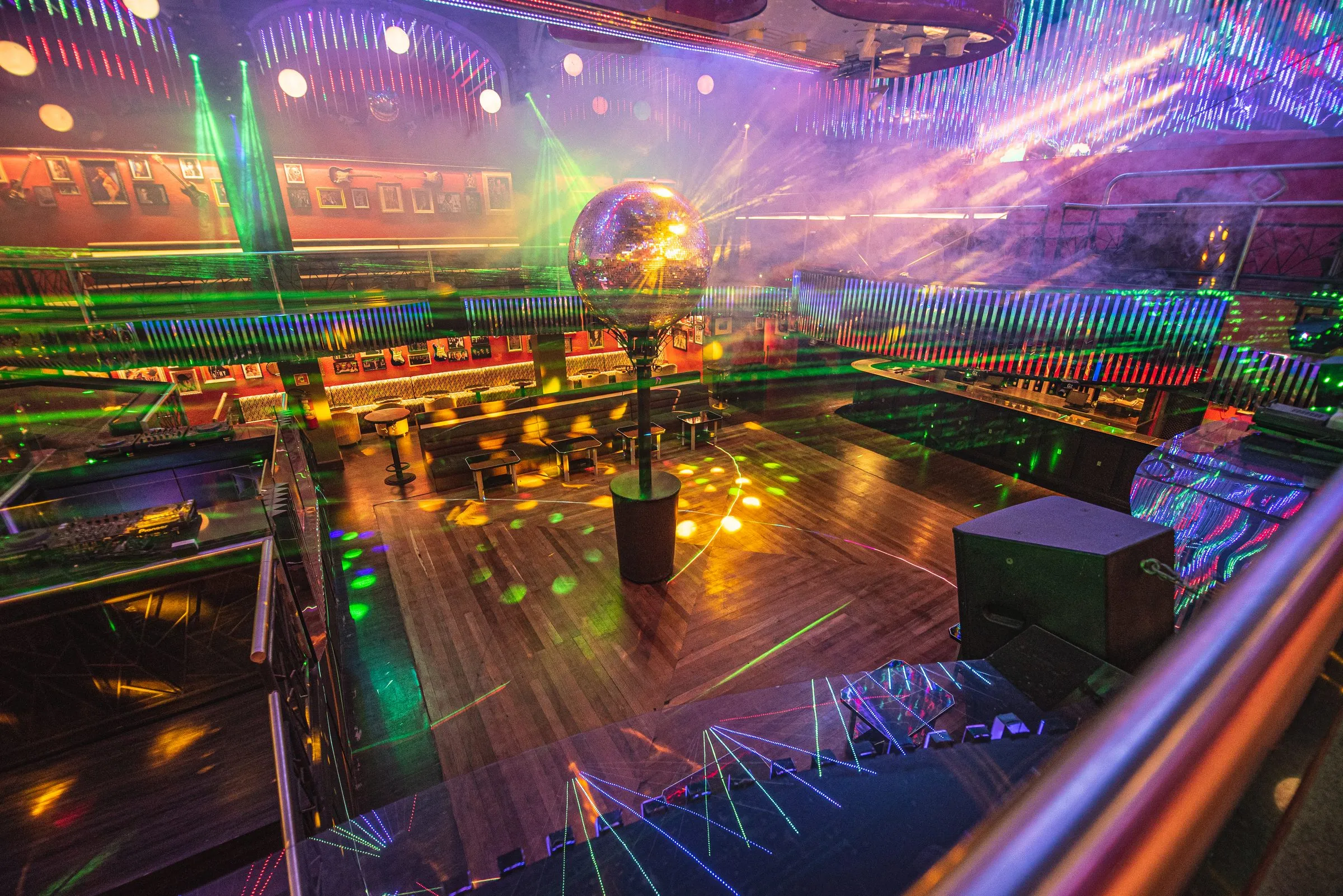 Pista da Limelight vista do mezanino, com o globo espelhado no centro do piso de madeira, lasers verdes, fumaça e reflexos coloridos, e os lounges e bares em volta