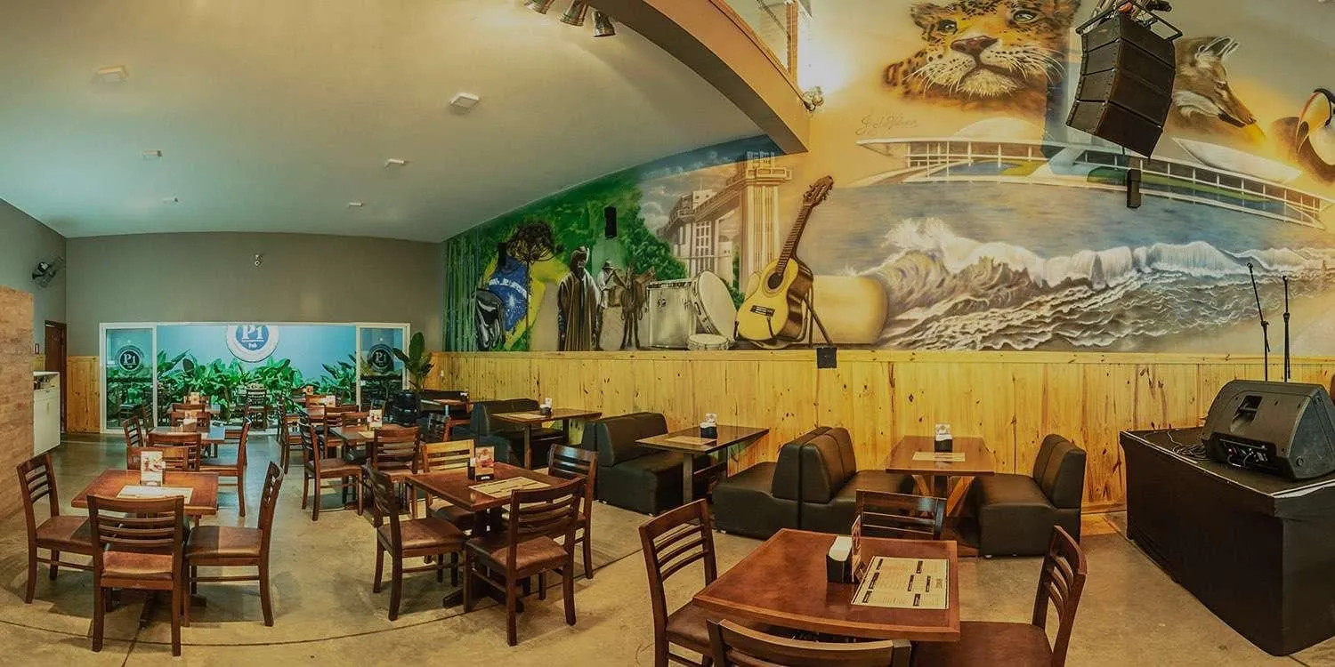 Salão do Posto 1 Pub Brasileiro, em Itapetininga, com mesas de madeira e mural pintado na parede