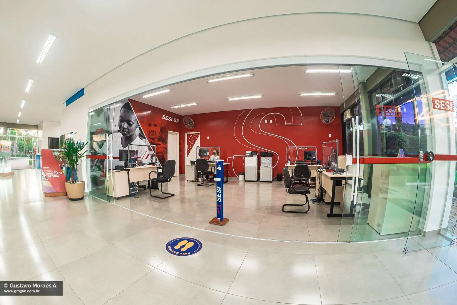 Recepção do SESI Itapetininga com balcões de atendimento e parede vermelha com a marca