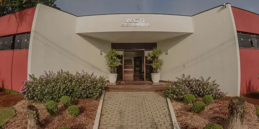 Fachada da WGB Seguros, com entrada central, vasos de plantas e jardim em frente